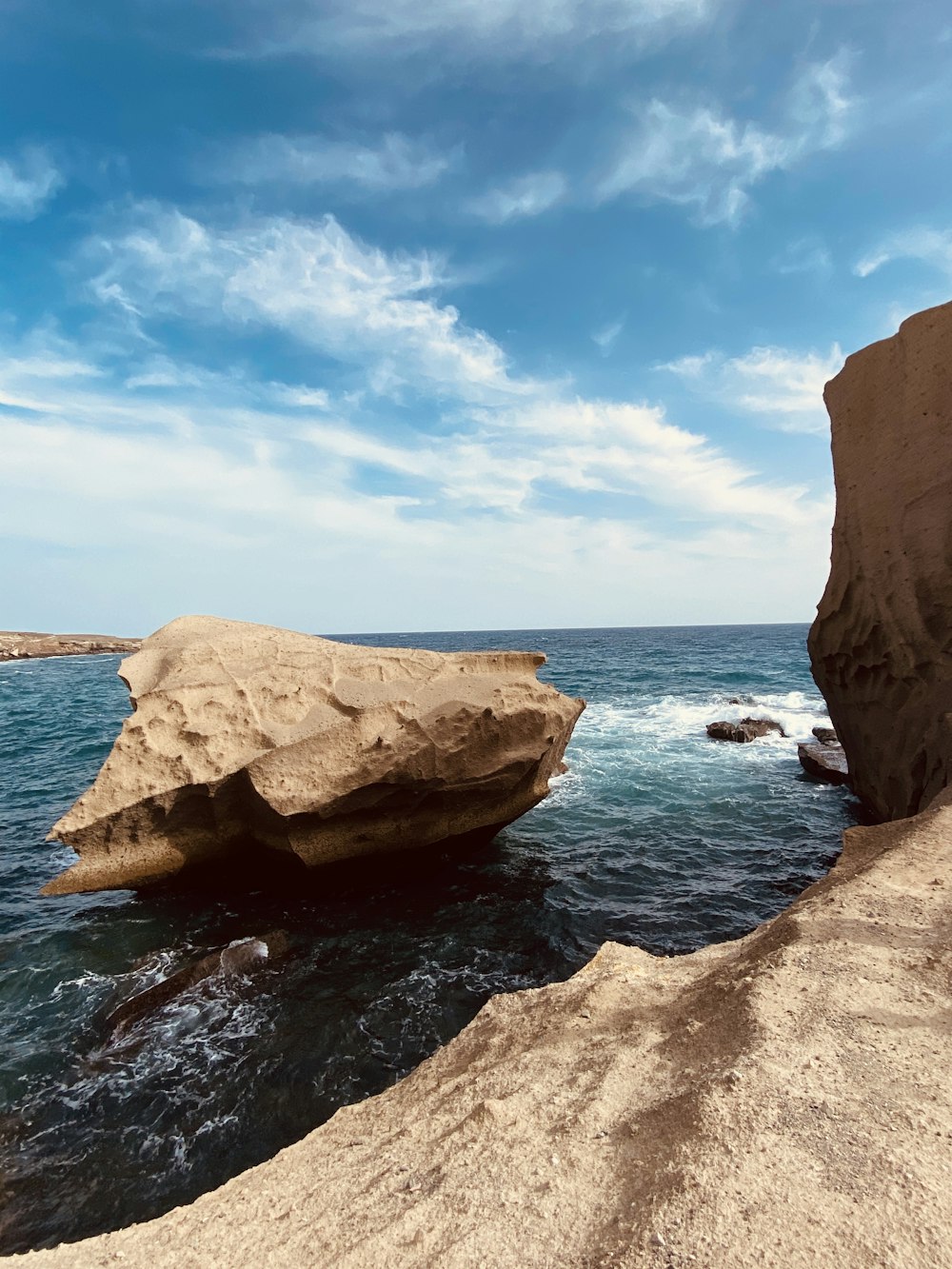 brown rock formation on sea under blue sky during daytime