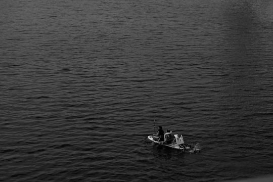 grayscale photo of man riding on boat on water in La Seine France