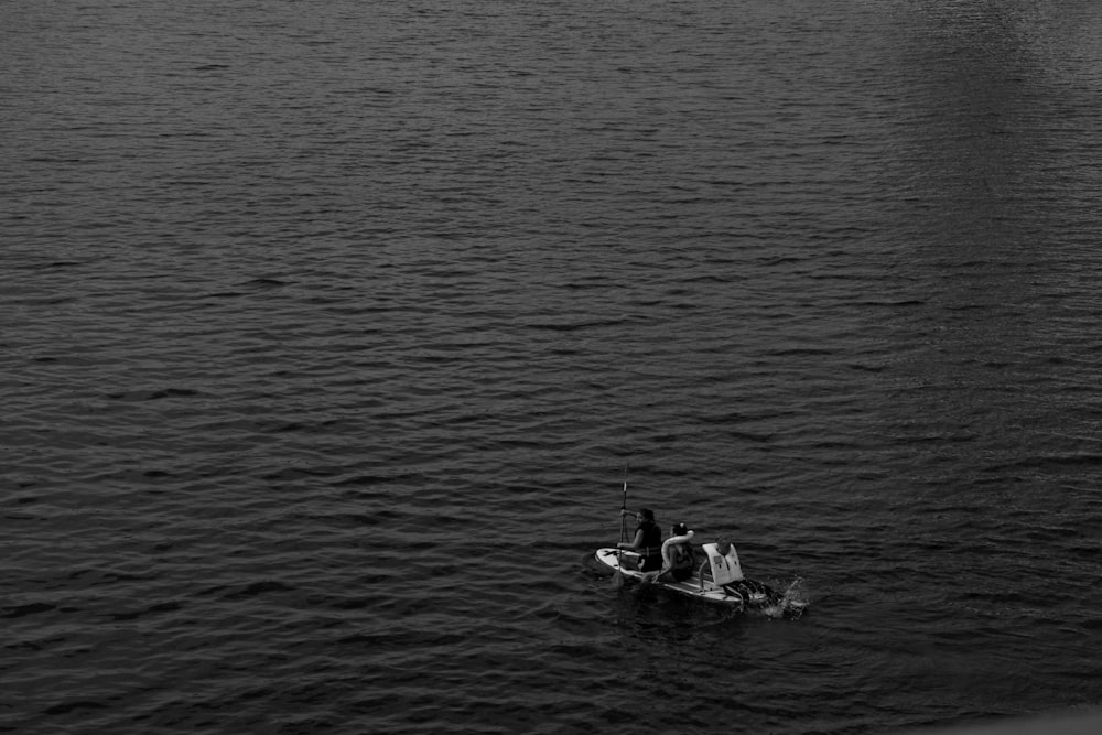 grayscale photo of man riding on boat on water