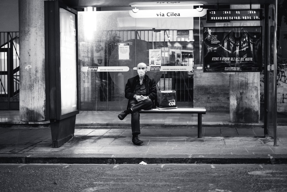 man in black jacket sitting on bench in front of store