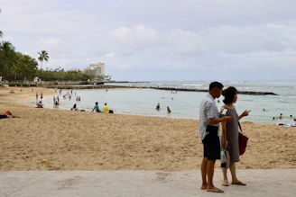 A friendly real estate agent discussing options with a young couple by the beach.