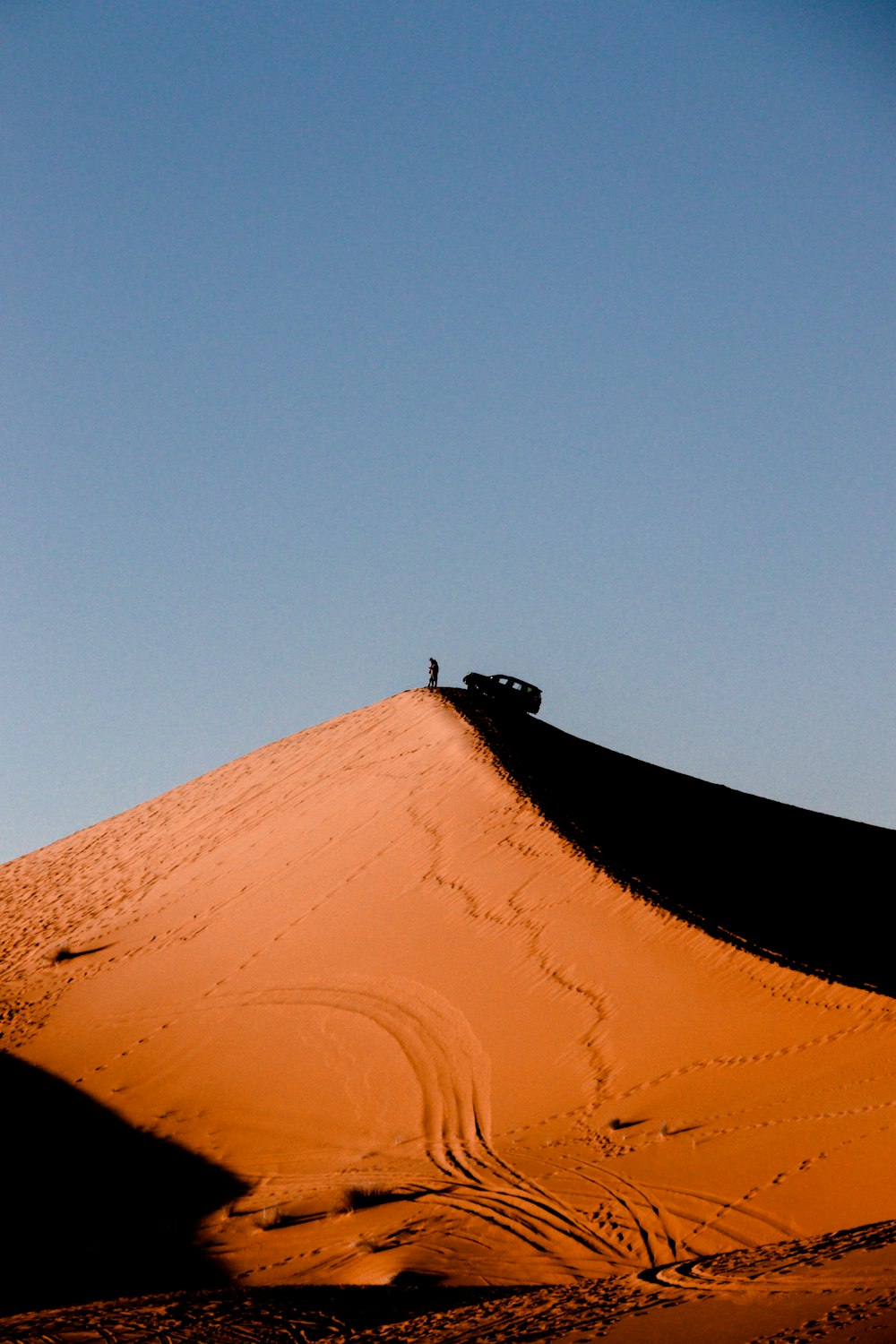 person in black pants and brown shoes standing on brown sand during daytime