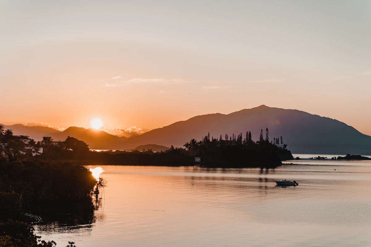 Coucher de soleil sur le lagon en Nouvelle-Calédonie, silhouettes d'arbres au bord de l'eau