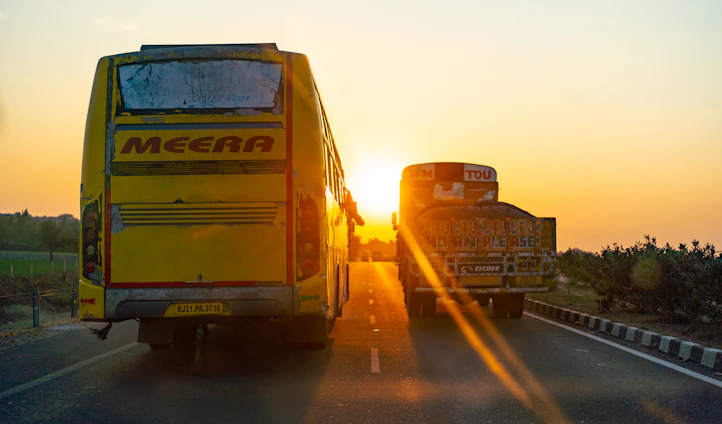 A vibrant blue and yellow delivery truck from Autónoma Latican driving along a highway at sunset.