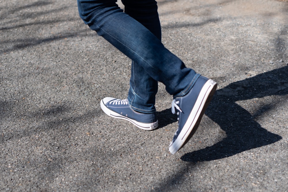 Persona con jeans de mezclilla azules y zapatillas Nike blancas y negras