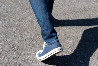 Casual street scene featuring a person walking with bright red All Star shoes and rolled-up jeans.
