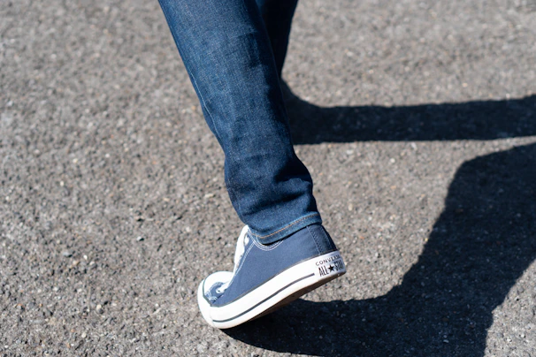 Casual street scene featuring a person walking with bright red All Star shoes and rolled-up jeans.