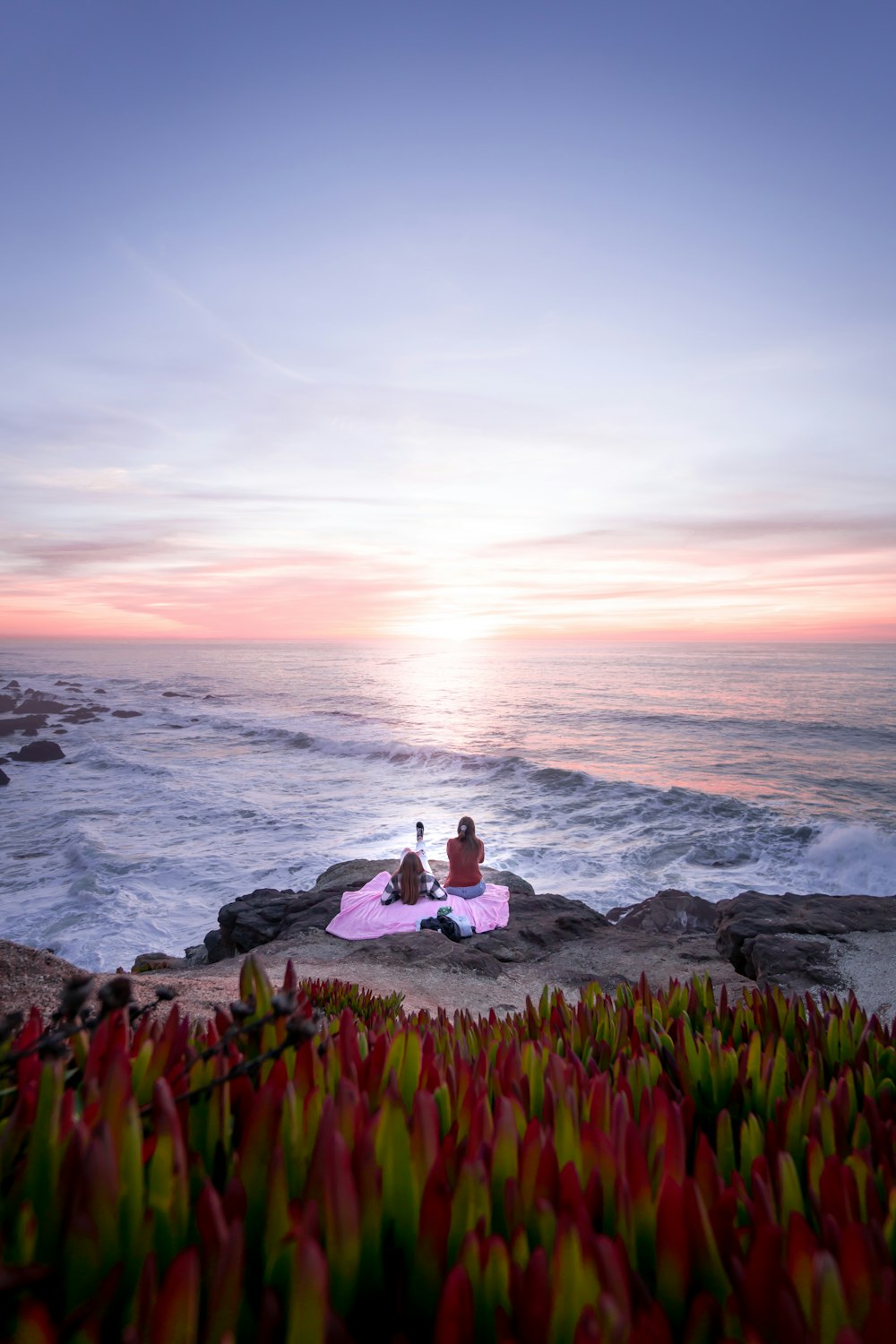 woman in white long sleeve shirt sitting on rock near sea during daytime