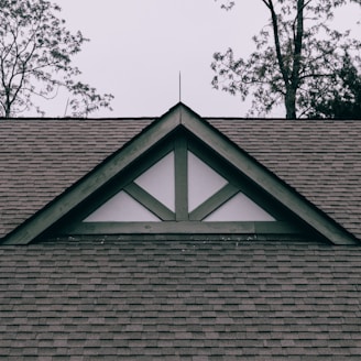 a roof with a triangle shaped window on top of it