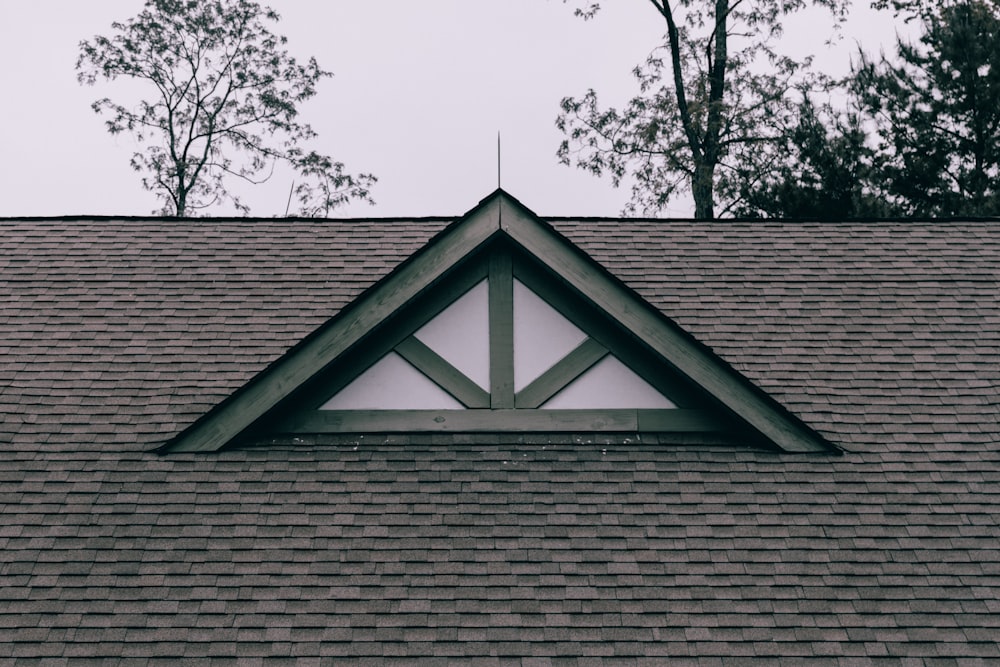 a roof with a triangle shaped window on top of it