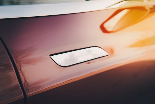 Close-up of a sleek black luxury door handle with warm golden reflections