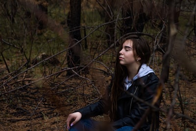 woman in black jacket sitting on brown grass during daytime deeply thoughtful zoom background