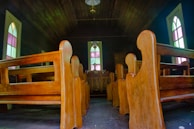 Interior of a parish church with wooden pews and stained glass windows.