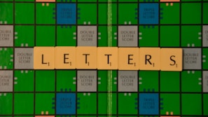 A Scrabble game board with green and blue squares is displayed, featuring beige letter tiles spelling out the word 'LETTERS' across it.