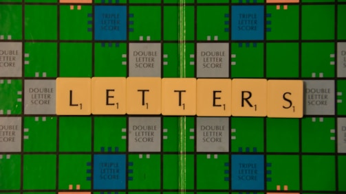 A Scrabble game board with green and blue squares is displayed, featuring beige letter tiles spelling out the word 'LETTERS' across it.