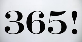 The image features the bold, black numbers '365!' centered on a plain, light background. The font has a vintage style with curved, ornate elements in the numbers.