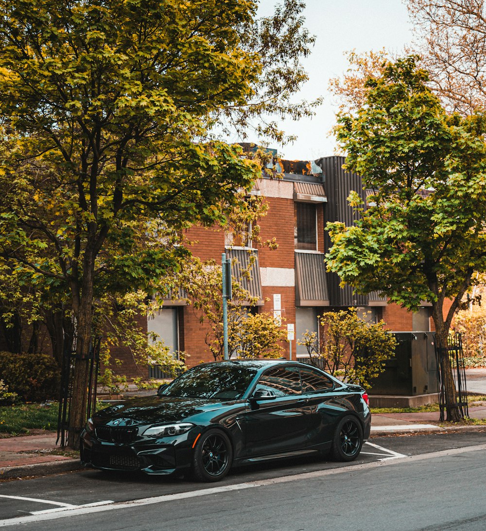 black sedan parked near brown concrete building during daytime