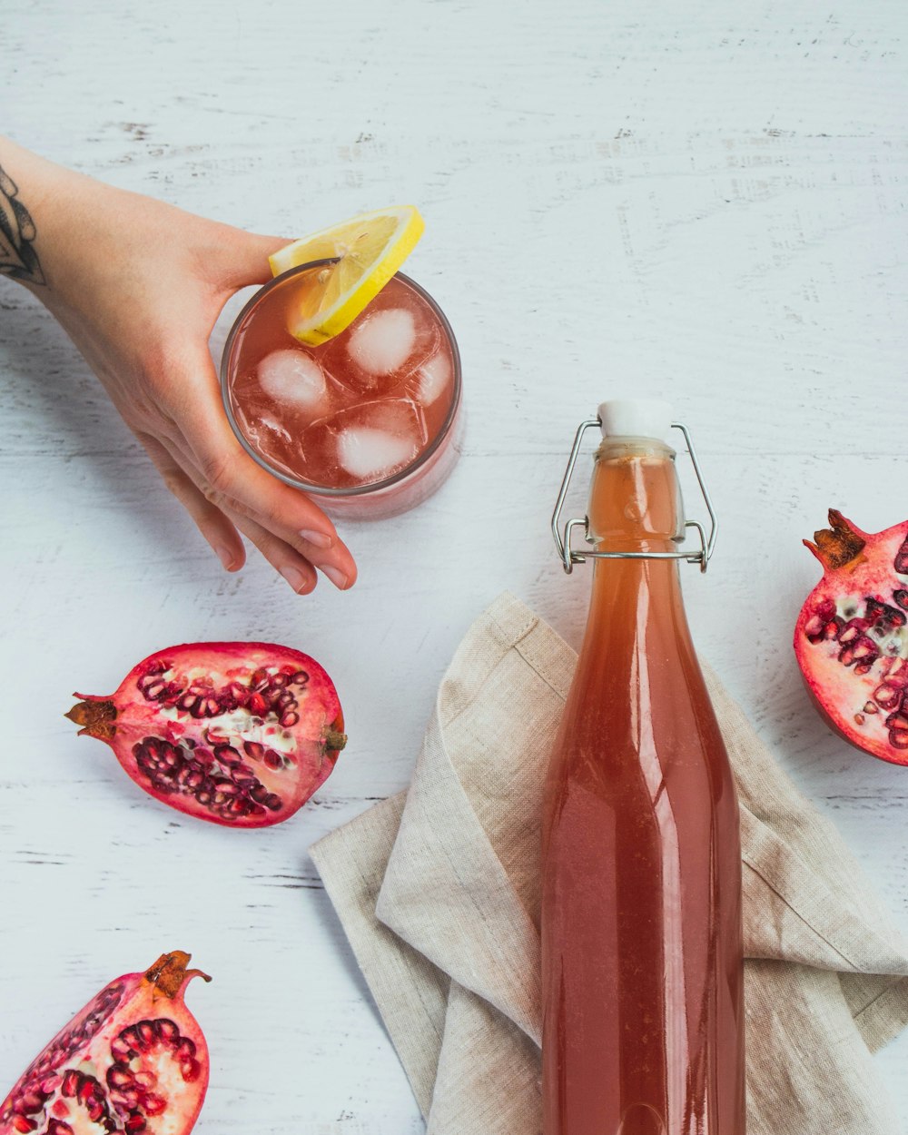 uma garrafa de romã ao lado de um copo de suco