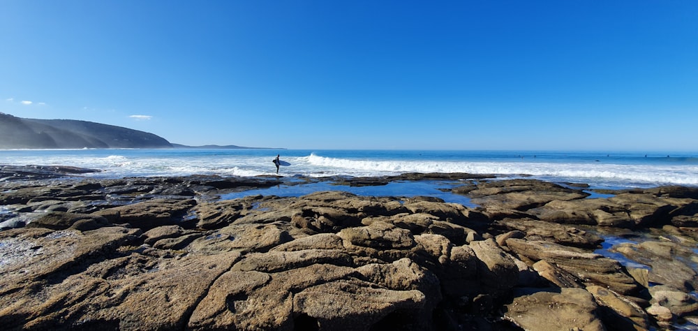 person standing on brown rock near sea during daytime