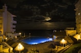 Night view of the hotel rooms softly lit, with the sea reflecting the moonlight.