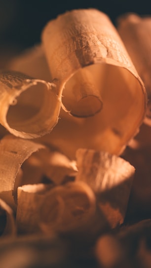 Close-up of rich wood shavings and leather scraps in warm natural light inside a craftsman's workshop.