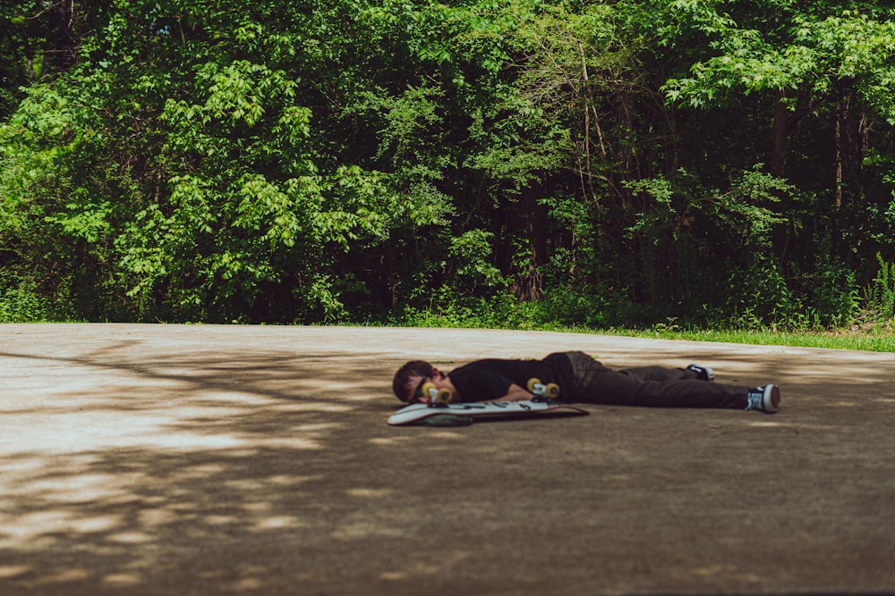 man lying on gray concrete road during daytime