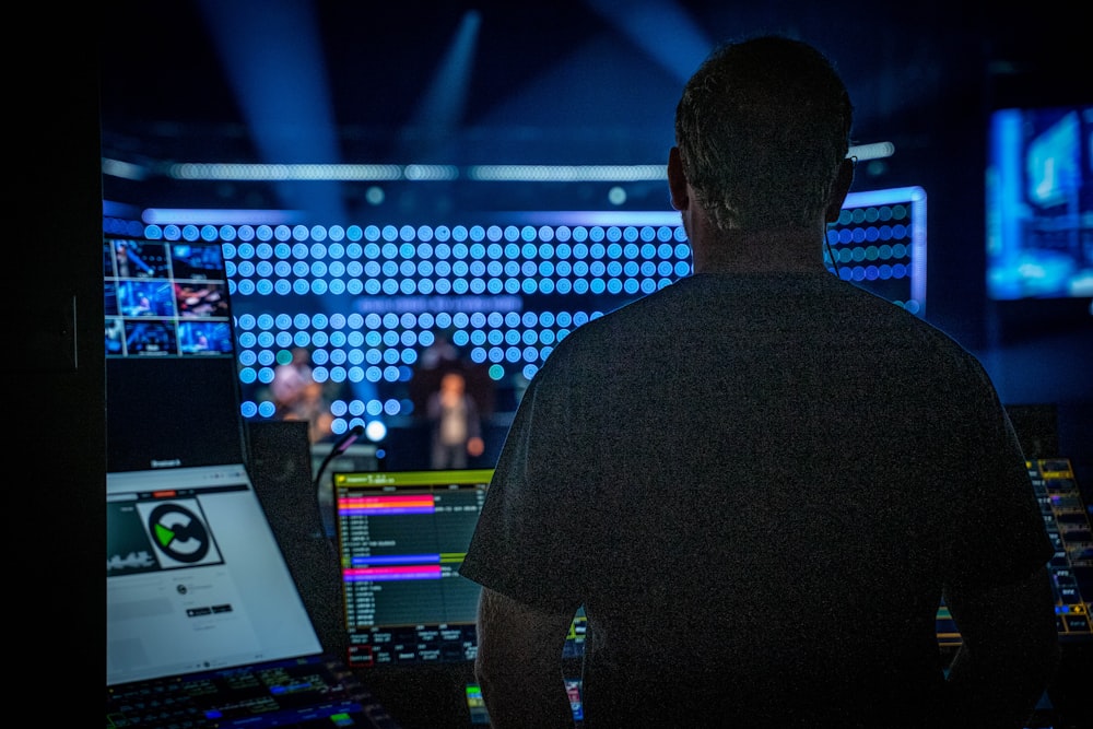 man in black shirt standing in front of audio mixer