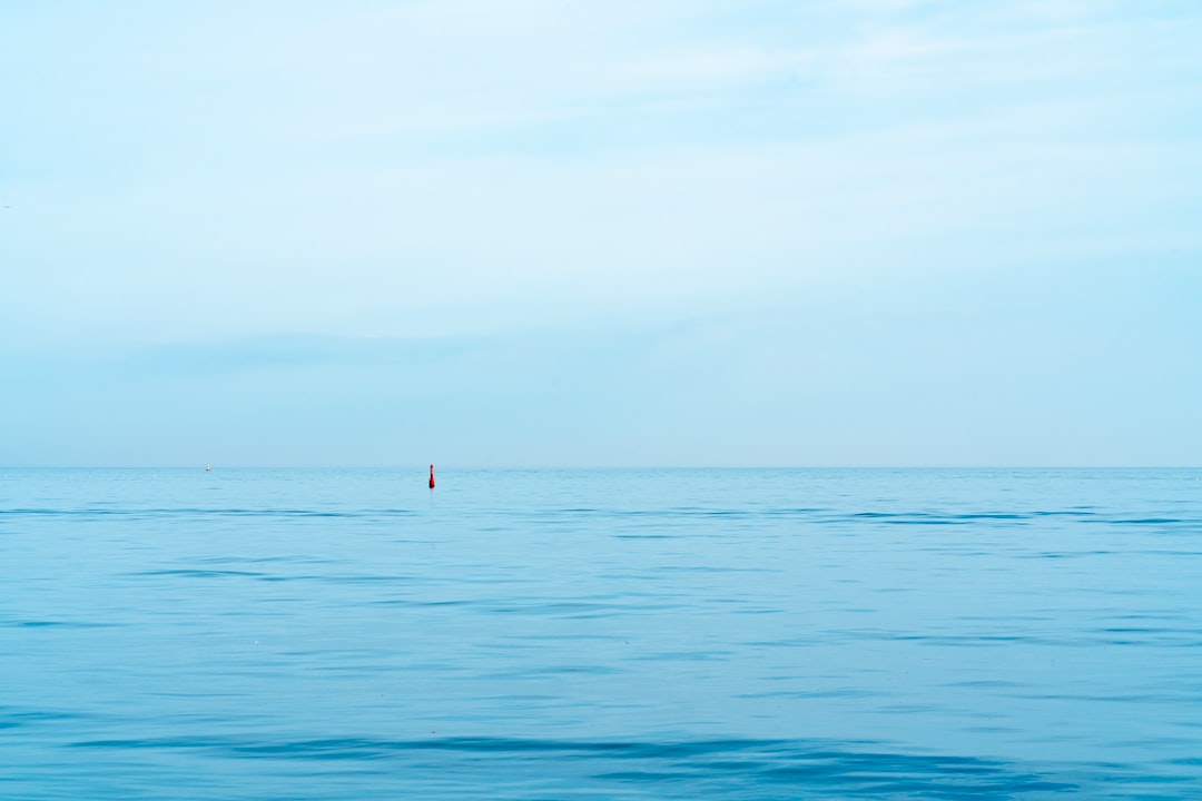 person in red shirt standing on blue sea during daytime
