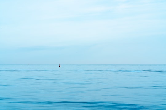 person in red shirt standing on blue sea during daytime in Lake Ontario Canada