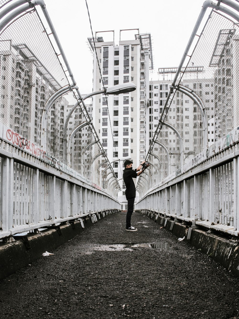 man in black jacket and black pants walking on bridge during daytime