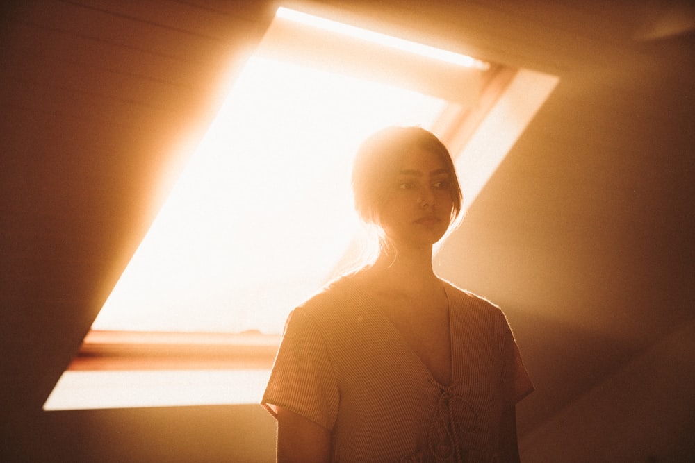 woman in white knit sweater standing near window during daytime