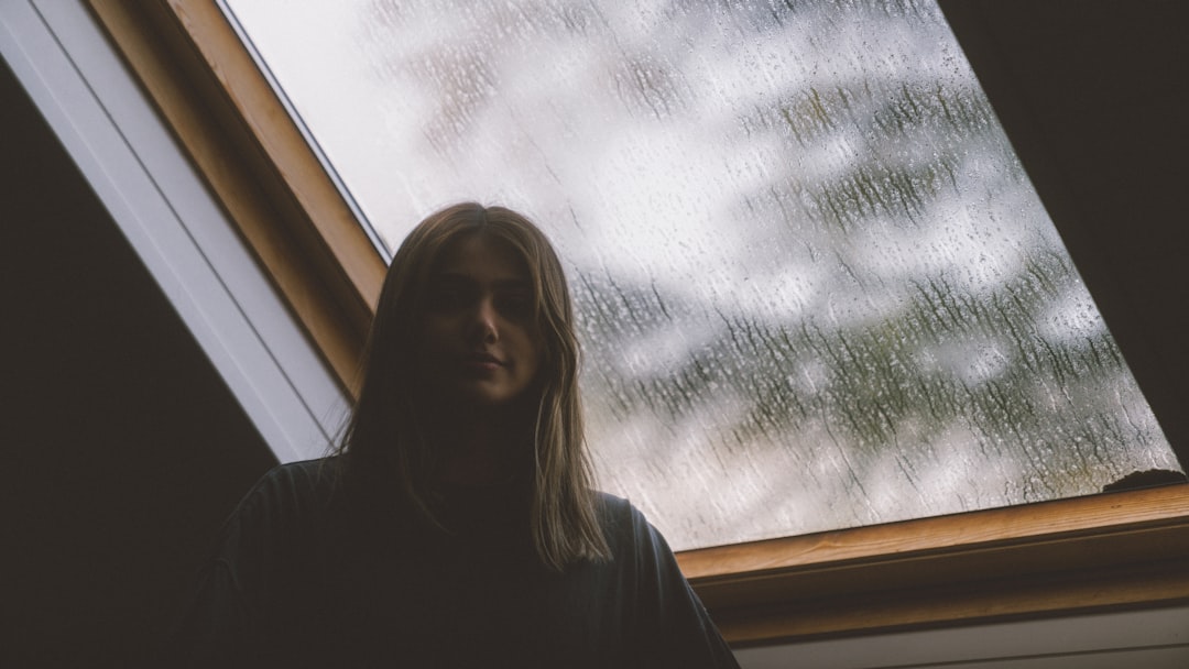 woman in black long sleeve shirt standing near glass window