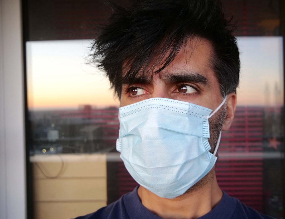 man in blue shirt wearing white face mask