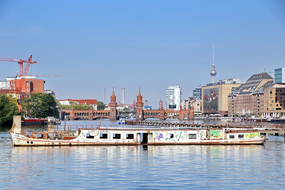 barco branco e marrom na água perto de edifícios da cidade durante o dia