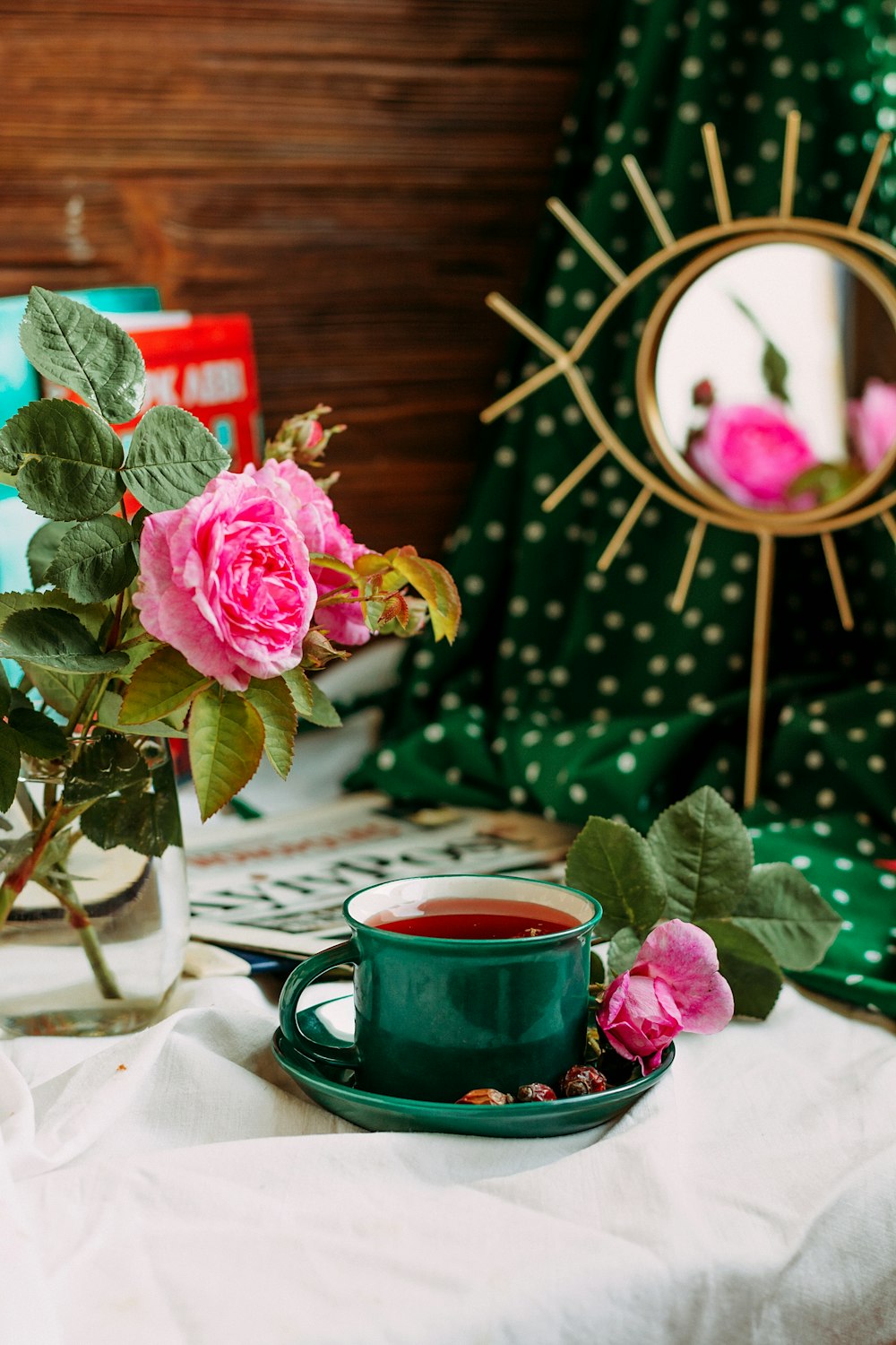 pink rose in glass vase beside red ceramic mug