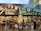 A vibrant mural depicting a diverse urban scene. The upper section features a pianist, people in formal wear, and officers with 'foreclosure' signage. The lower section shows urban life with people, pets, a classic car, police officers, and various street elements against colorful houses and buildings.