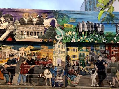 A vibrant mural depicting a diverse urban scene. The upper section features a pianist, people in formal wear, and officers with 'foreclosure' signage. The lower section shows urban life with people, pets, a classic car, police officers, and various street elements against colorful houses and buildings.