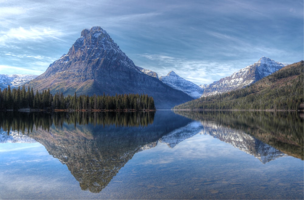 green and brown mountain beside lake under blue sky during daytime