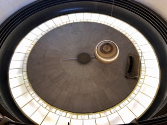 A large pendulum swings above a circular platform with marked numbers around its circumference. The setting appears to be indoors, with a focus on the pendulum's central movement and surrounding numbered markers.