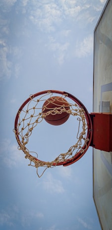 A dynamic shot of a youth basketball player leaping for a dunk against a clear sky.