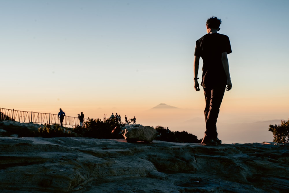 man in black t-shirt standing on snow covered ground during sunset