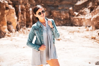 A stylish woman wearing a retro jacket and smiling in natural sunlight outdoors.