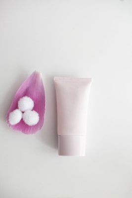 Elegant tube of gentle vegan cleanser surrounded by delicate pink petals and soft shadows, highlighting its pure and calming formula.