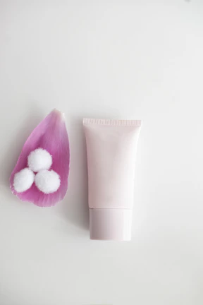 A delicate pink flower beside a serum bottle, set against a minimalistic background