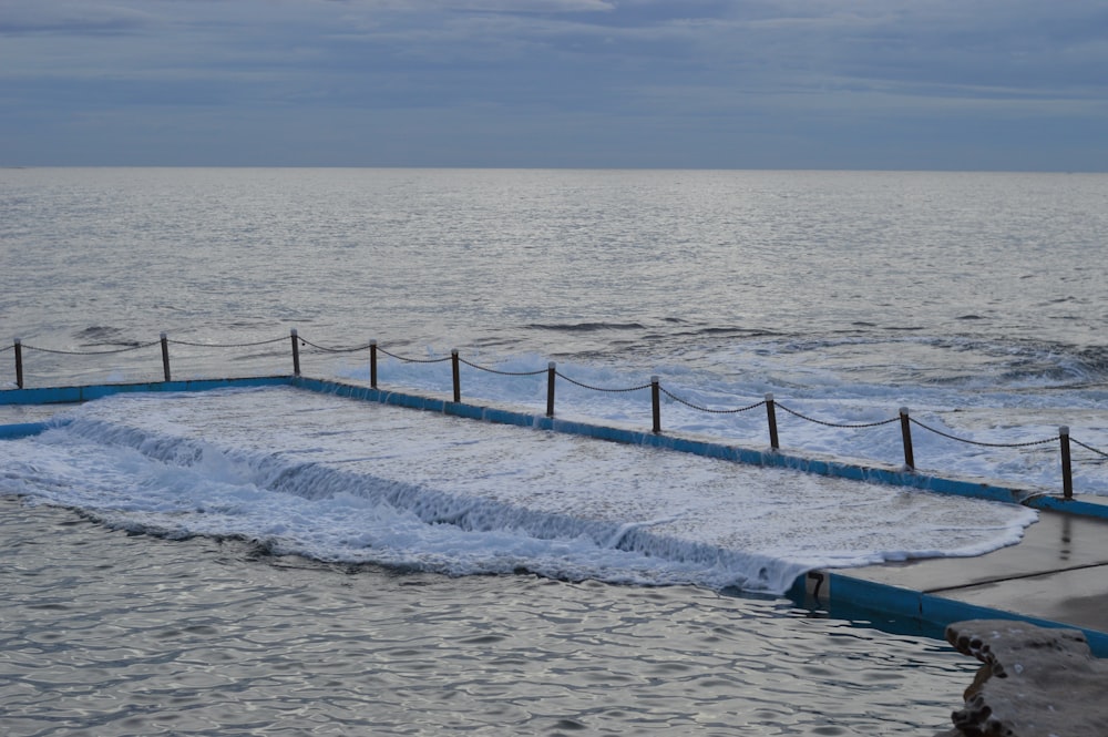 blue wooden fence on beach during daytime