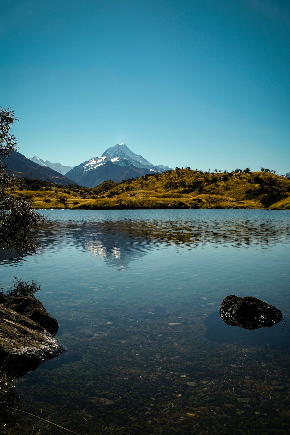 lake near mountain under blue sky during daytime