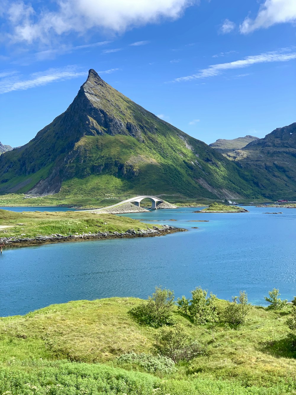 green mountain beside body of water during daytime