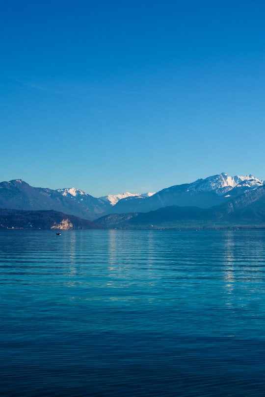 blue body of water near mountain under blue sky during daytime in Annecy France