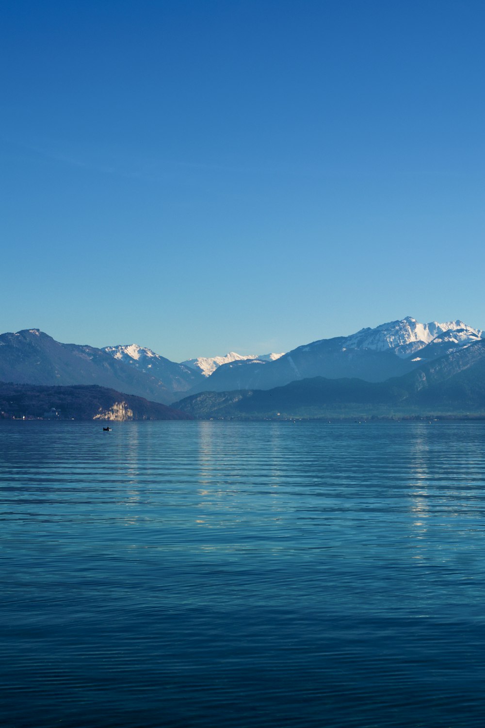 blue body of water near mountain under blue sky during daytime