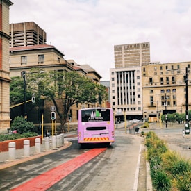red and white bus on road near brown concrete building during daytime